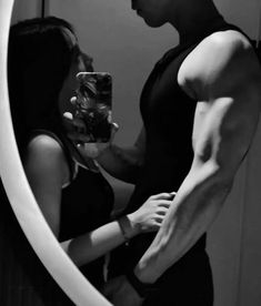 a man taking a selfie in front of a mirror with a woman standing next to him