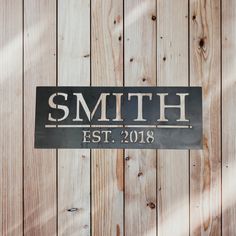 a sign that says smith est 2018 on it next to wood planked wall with the name