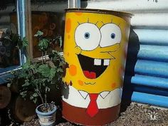 a yellow trash can with a cartoon character painted on it's side next to a potted plant