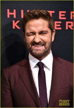 a man in a suit and tie smiling at the camera with his eyes wide open