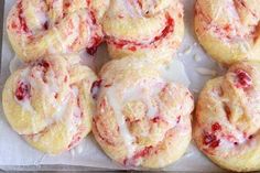 several pastries with white icing and strawberries on top