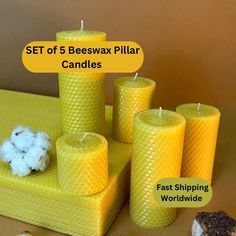 four beeswax pillar candles are sitting on a table with cotton balls and other items