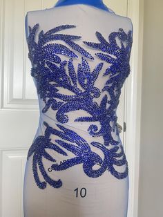 a mannequin with blue beads on it's torso and back, sitting in front of a door