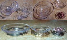 four different glass bowls with lids and spoons next to each other