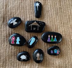 six painted rocks arranged in the shape of houses and people on them, sitting on a brown surface