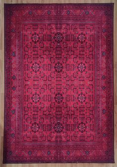 a red rug with an intricate design on the center and sides, sitting on a wooden floor