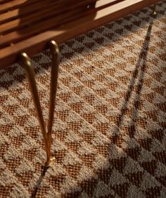 a wooden bench sitting on top of a carpeted floor next to a metal pole