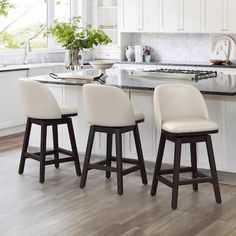 three white stools sit at the center of a kitchen island