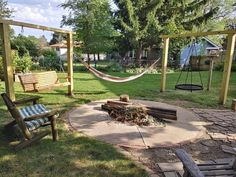 a backyard with swings, chairs and a fire pit