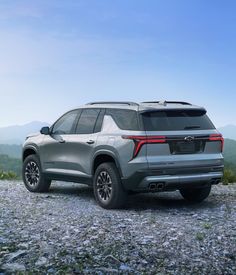 the rear end of a silver suv parked on top of a mountain