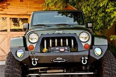 the front end of a jeep parked in front of a garage