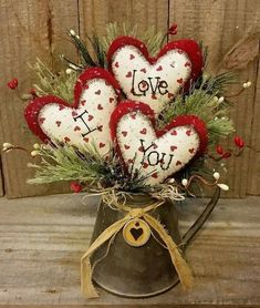 four heart - shaped ornaments in a watering can with the words i love you on them