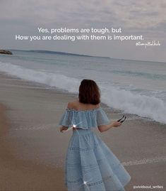 a woman standing on top of a beach next to the ocean holding a cell phone