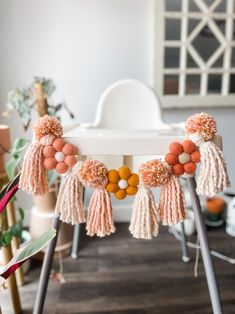 an orange and white tasselled garland with pom poms hanging from it