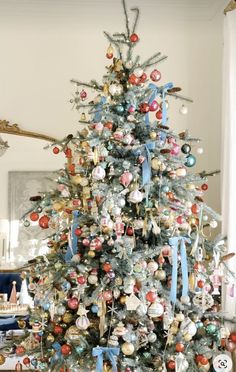 a decorated christmas tree in a living room with blue ribbon and ornaments on the top