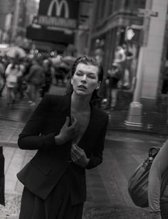 black and white photograph of a woman standing on the sidewalk