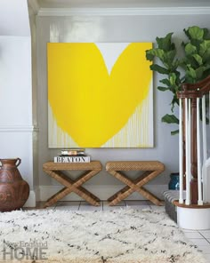 a living room with a painting and two stools in front of the rug on the floor