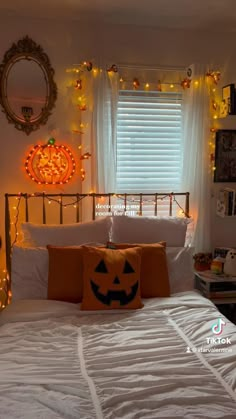 a bedroom decorated for halloween with pumpkins on the bed and lights strung from the window