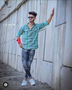 a young man is standing in front of a wall with his hand up to the side