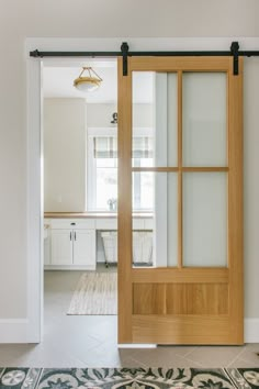 an open wooden door with glass panels in a white room next to a rug on the floor