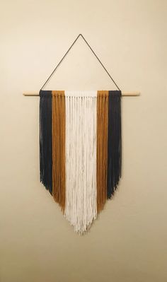 a wall hanging with fringes on it in the shape of a triangle and two different colors