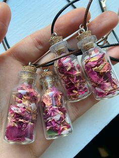 three glass bottles filled with pink and purple flowers sitting on top of a black cord