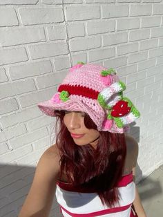 a woman wearing a pink crocheted hat with cherries on it