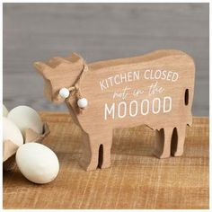 a wooden cow with the words kitchen closed next to it and some eggs in front of it