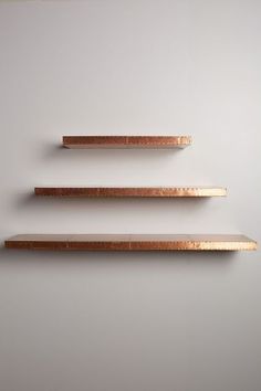 three wooden shelves are lined up against the wall