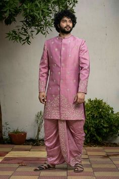 a man in a pink outfit standing on a tiled floor next to a tree and bushes