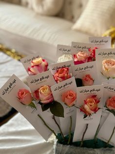 there are many cards with roses in them on the table next to a bed and pillows