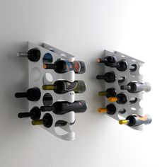 two wall mounted wine racks holding bottles of wine on the side of a white wall