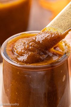 a spoon full of peanut butter on top of a jar