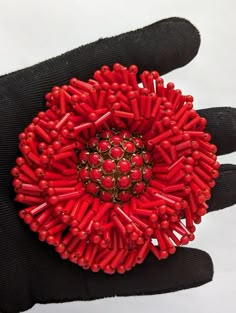 a red flower brooch sitting on top of a black glove