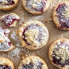 cookies with powdered sugar and jam are arranged on a baking sheet