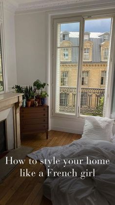 a bedroom with a fireplace, bed and window overlooking the city in french style home