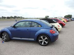 a row of parked cars sitting next to each other in a parking lot on a cloudy day