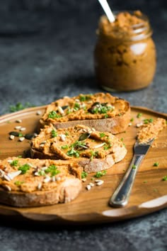 some food is on a wooden plate with a knife and fork next to the bread