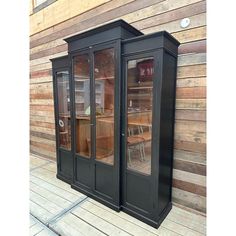 two black glass doors on the side of a wooden wall next to a table and chairs