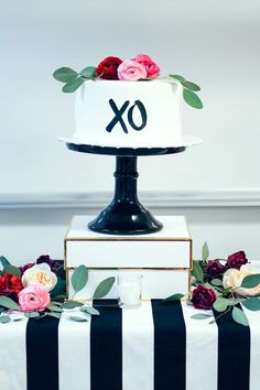 a black and white striped table cloth topped with a multi - tiered cake covered in flowers