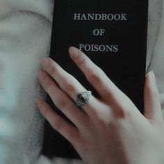 a person's hand on top of a book with a ring on their finger