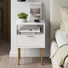 a white nightstand with books on it next to a bed