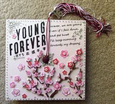 a card with pink flowers on it that says, young forever bits are hanging from a string