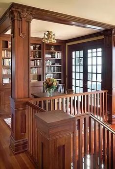 a room with wooden floors and bookshelves filled with books on the shelves, along with a vase full of flowers