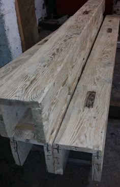 a wooden bench sitting inside of a building next to another piece of wood on the ground