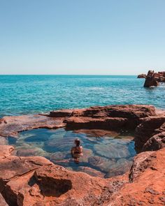 a person sitting in the water near some rocks