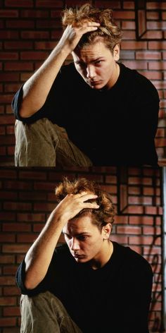 a young man sitting down with his hands on his head and looking at the camera