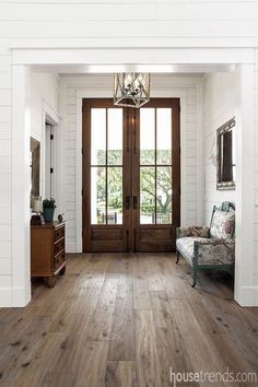 an iphone photo of a living room with wood flooring and french doors that lead to the front door