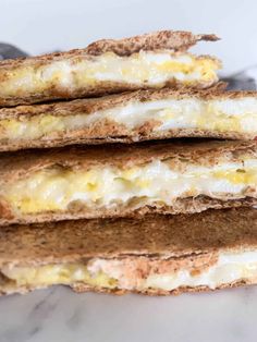 three sandwiches stacked on top of each other with cheese and eggs in between them,