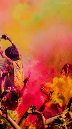 a group of people covered in colored powder and throwing colors at each other with their hands